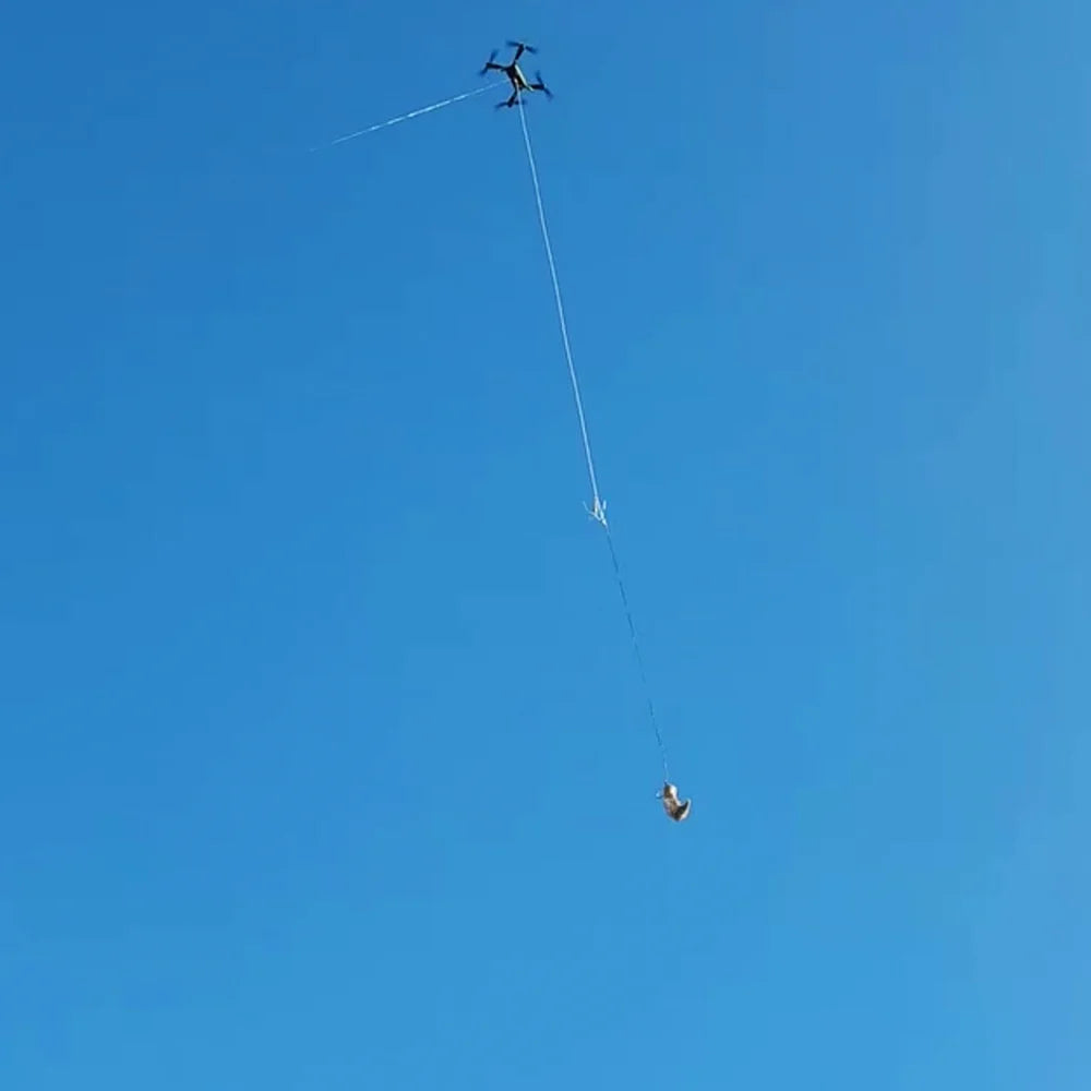 Xpece Rescue Drone flying with a suspended payload on a tether against blue sky